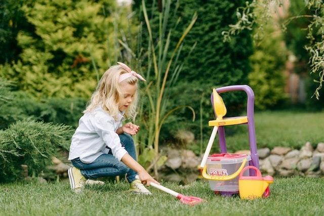 A girl playing with plastic toys in the backyard.