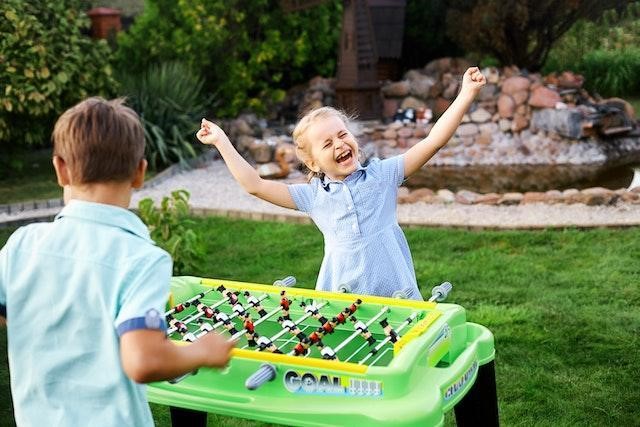 A boy and a girl playing foosball table.