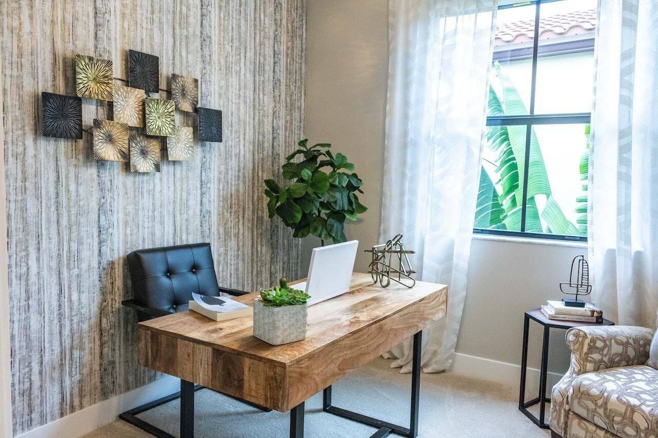 A home office with a wooden desk and some plants.