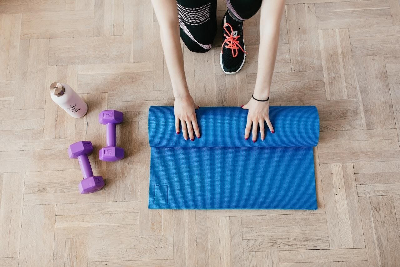 A person unpacking a yoga mat at their home gym, which Is one of the best home remodel projects