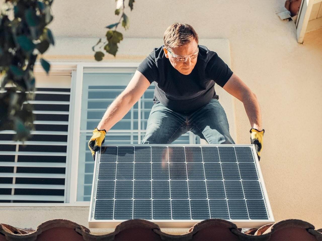 A man putting a solar panel on a roof.